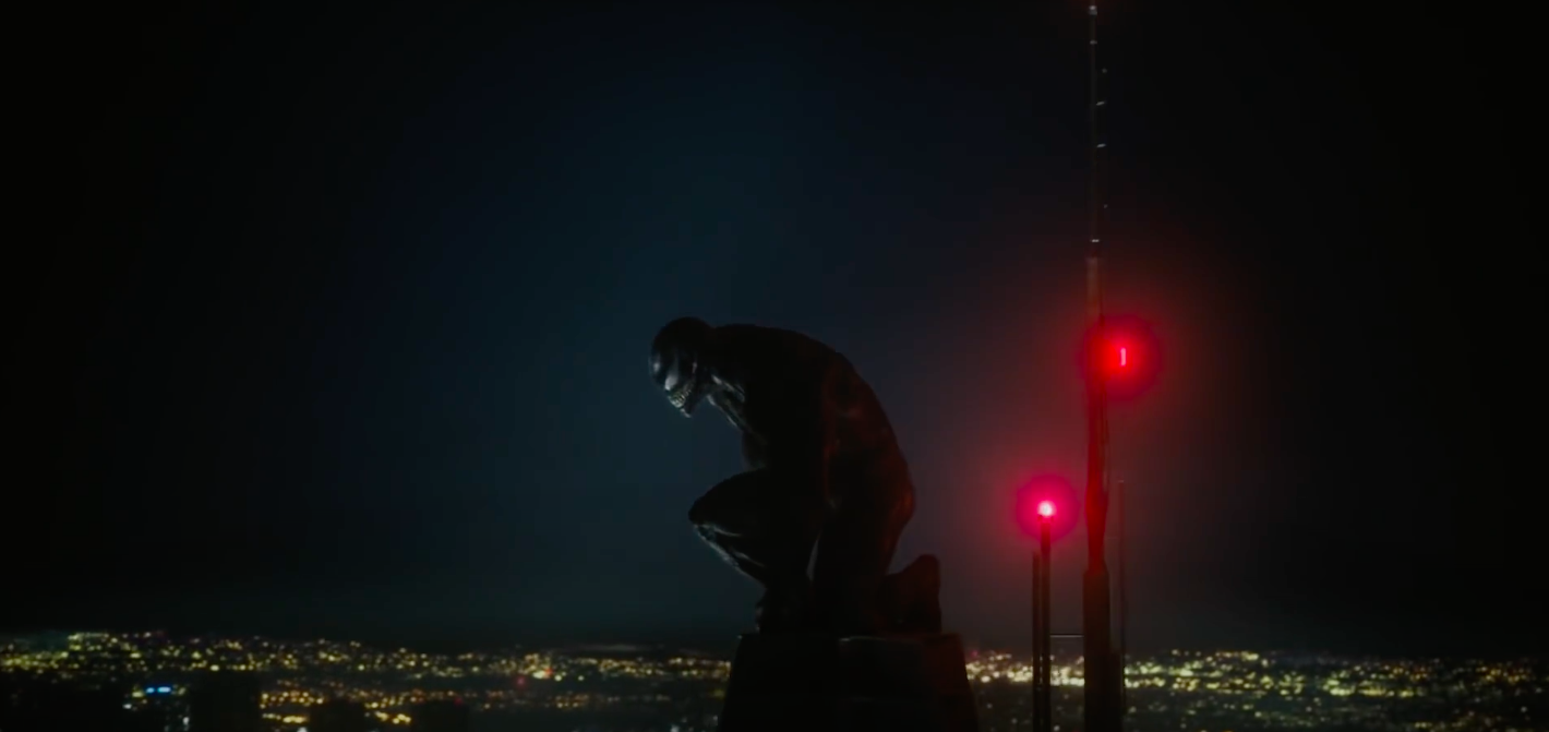 A still of Venom at the top of a tower at night looking down at the city